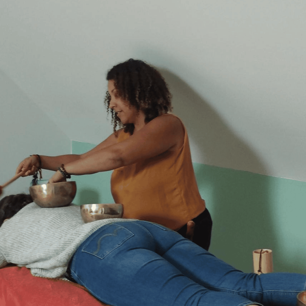 Coralie, praticienne chez Chœur Intérieur, réalisant un massage sonore aux bols tibétains sur le corps d'une cliente dans le cadre de l'accompagnement Voyage Symphonie en Essonne.