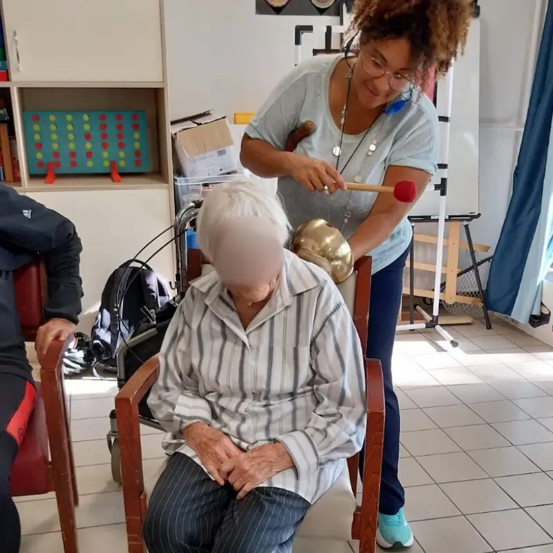 Coralie, praticienne Chœur Intérieur, anime un atelier de médiation sonore pour les aînés en EHPAD en Essonne, utilisant les vibrations des bols tibétains pour le bien-être cognitif